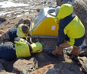 Two men lay on rocks securing radio equipment