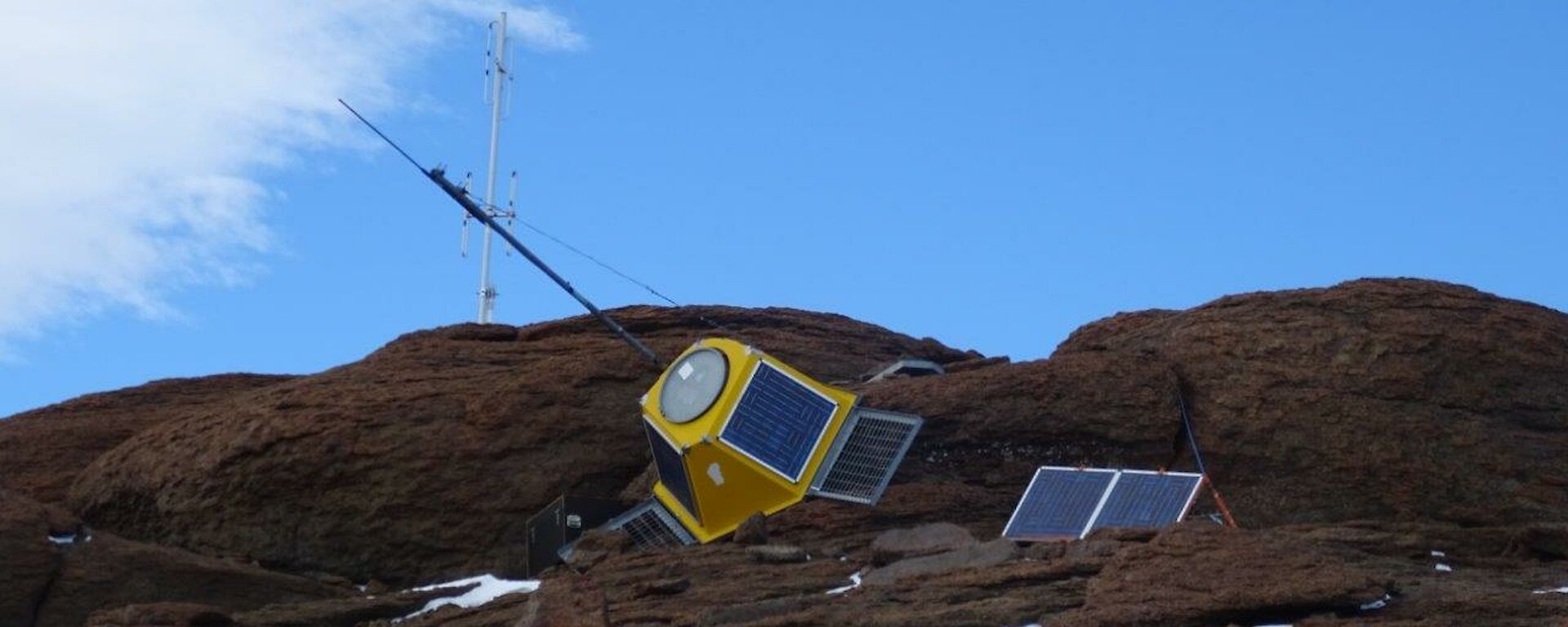 A yellow encased radio transmitter sits fallen against rocks