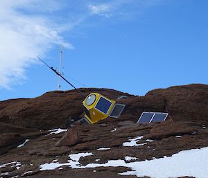 A yellow encased radio transmitter sits fallen against rocks