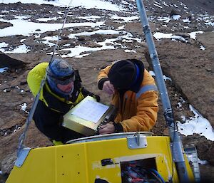 Two men inspect electrical equipment inside the radio unit