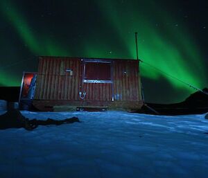 Green auroral light behind a red field hut