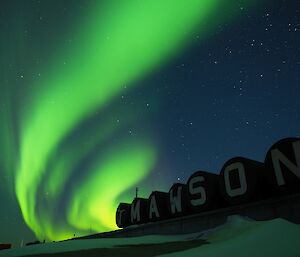 A green aurora behind the fuel tanks at Mawson Station