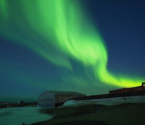 A green auroral display behind the historic hangar on station