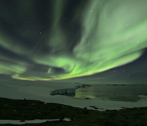 A green and white aurora over Kista Strait at Mawson station