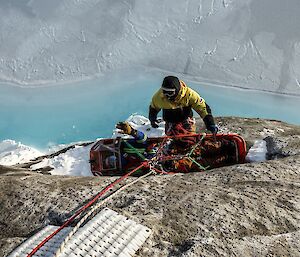 a man is hauling a stretcher over a cliff edge