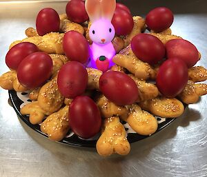 a platter of biscuits and red dyed eggs sit on a bench