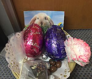 a basket contains easter eggs, chocolates and a photo of the Easter Bunny