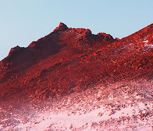 a mountain range glows red and purple at dusk