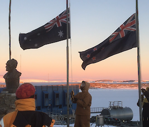 two men lower the Australian and New Zealand flags