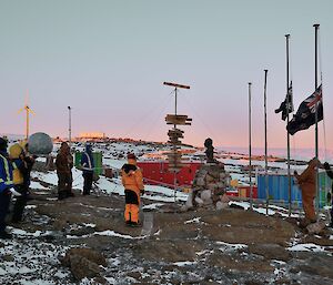 a group of expeditioners watch as flags are lowered to half mast