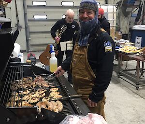 a man wearing a balaclava prepares a BBQ