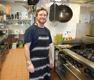 a chef stands in the kitchen wearing an apron