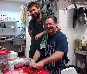 A man is leaning on the shoulder of a chef wearing an apron