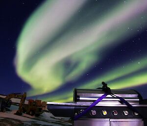 A BBQ sits in front of a green and violet aurora