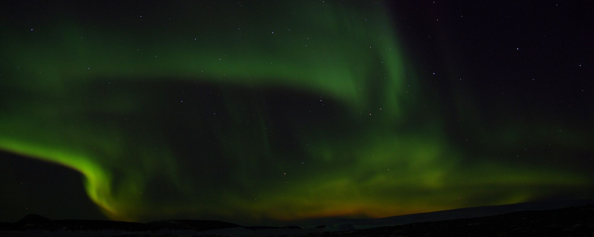 Orange and green flames seem to be rising from the black horizon