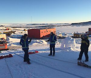 A group of expeditioners stand in front of the pulleys on the ice