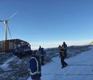 A group of expeditioners stand in front of a blue Hägglunds