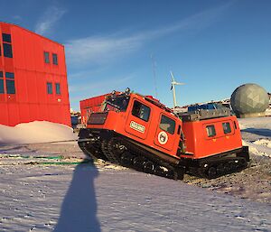 A red Hägglunds vehicle is towed over an ice edge