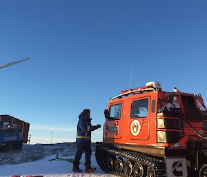 A man stands next to a red Hägglunds vehicle