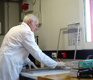 A man in a white coat stands in front of a metal frame