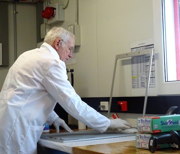 A man in a white coat stands in front of a metal frame