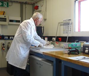 A man in a white coat stands in front of a metal frame