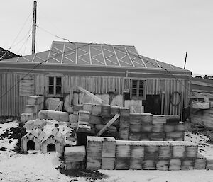 A black and white photo of a wooden hut in snow