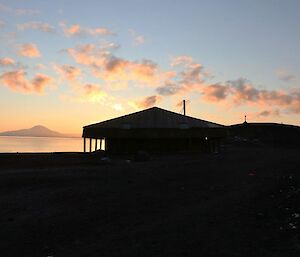 The outline of a dark hut at sunrise