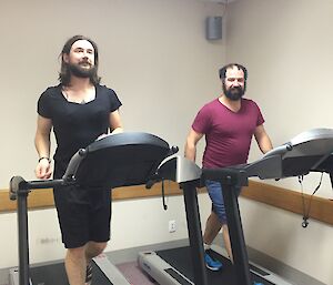 Two men walk side by side on treadmills