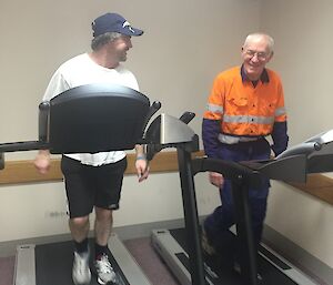 Two men walk on treadmills next to one another