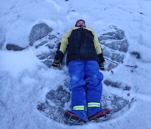 A man lies in the snow with wings like an angel