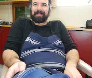 A man sits wearing a chef apron