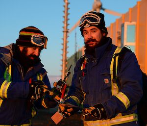 Two expeditioners hold a radio