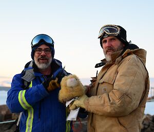 Two expeditioners hold a stuffed toy cat