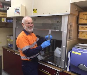 A man in high visibility clothing is measuring liquid in a test tube