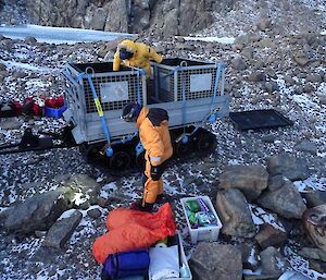 Two people load up a trailer with tubs and bags