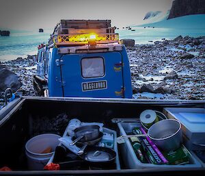 A trailer full of kitchen materials are towed behind a blue Hägglunds vehicle.