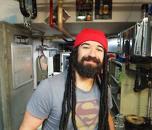 A man with a dreadlocked wig smiles.