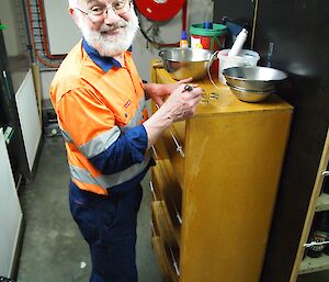 A man in high visibility clothing writes on bottle caps.