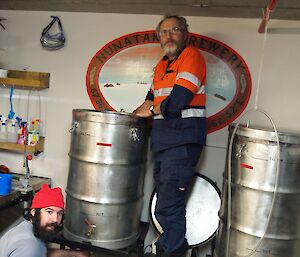 Two men cleaning beer kegs.