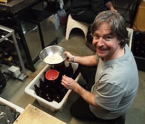 A man adds sugar to beer bottles.