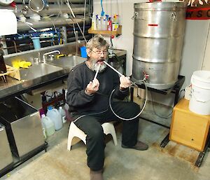 A man sits with two hoses poking into his mouth.