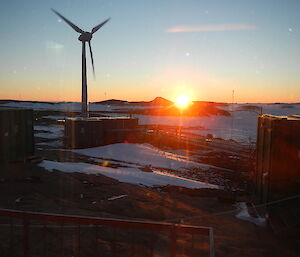 A sun set with a windmill in the front.