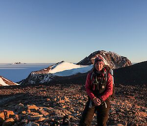 A woman stands on a rocky mountain.