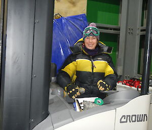 A woman sits in a forklift.