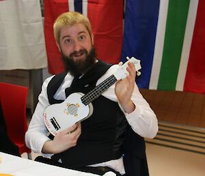 A man holds a white ukulele.
