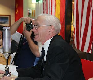 A man laughs in front of a microphone.