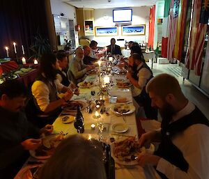 People are sitting at a long table formal dinner.