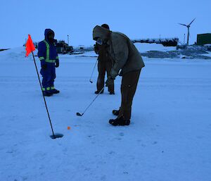 three people stand on a frozen golf course