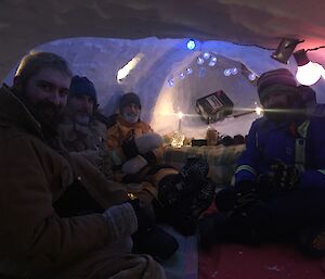 Four people in antarctic clothing are inside an ice cave.
